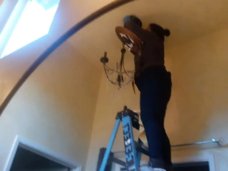 Electrician installing a chandelier in a Gas City residence
